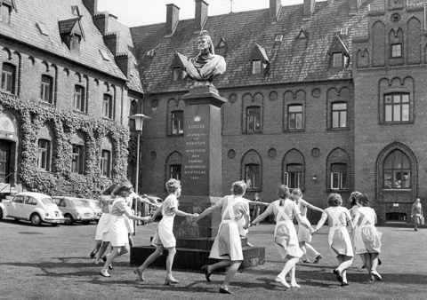 Billedet viser en gammel tradition, hvor nyuddannede fra Diakonissestiftelsen danser om Dronning Louises buste.